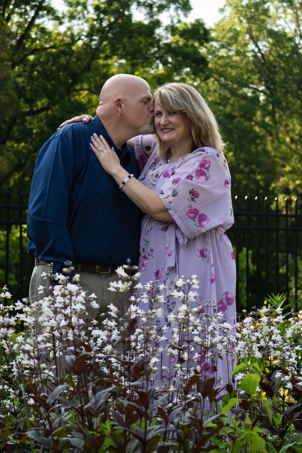 A tender moment captured in a garden with blooming white flowers in the foreground.