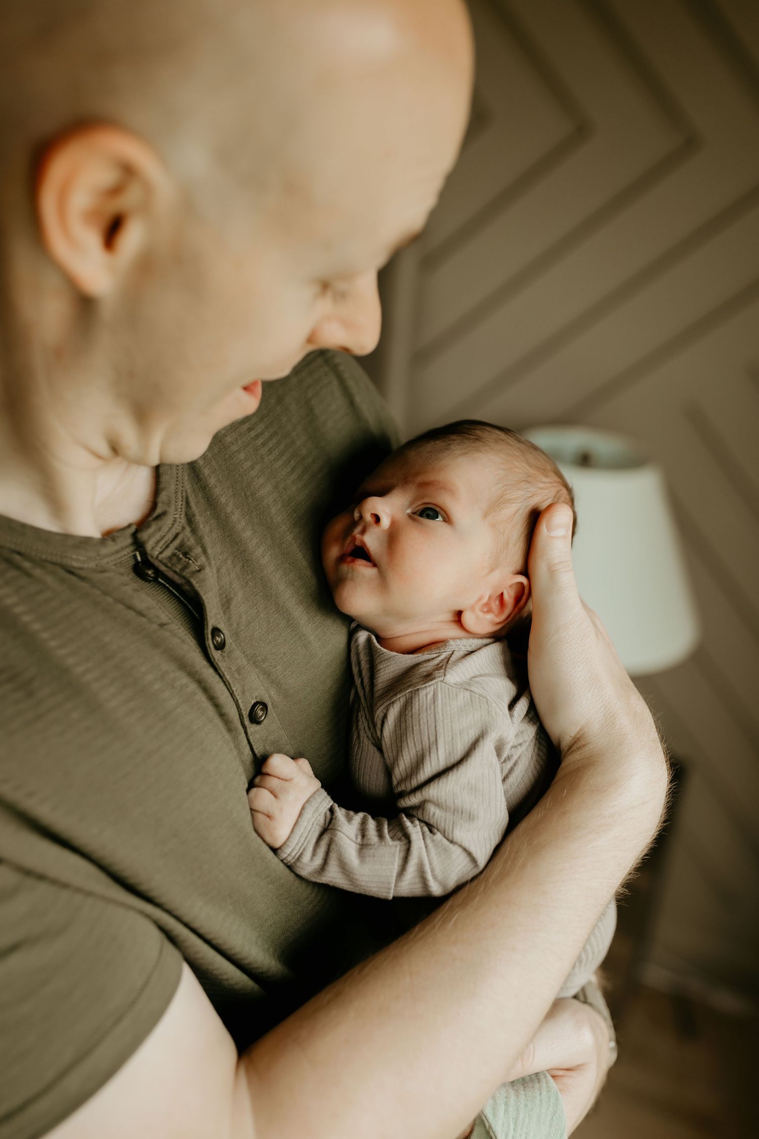 A tender moment between parent and newborn baby as they cuddle close together in soft lighting.