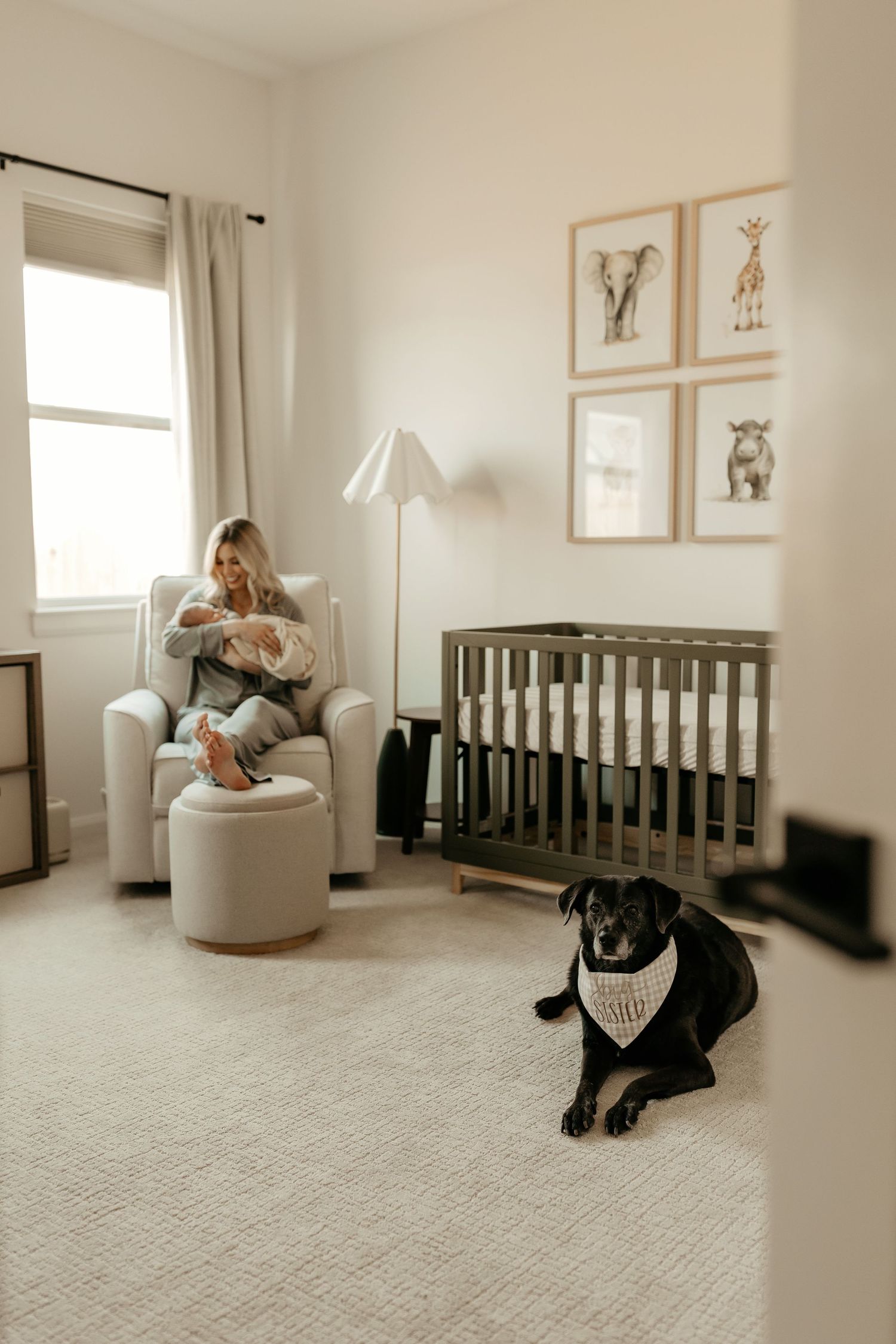 A cozy white nursery room with a crib, swivel chair, and wall art displayed in simple wooden frames.