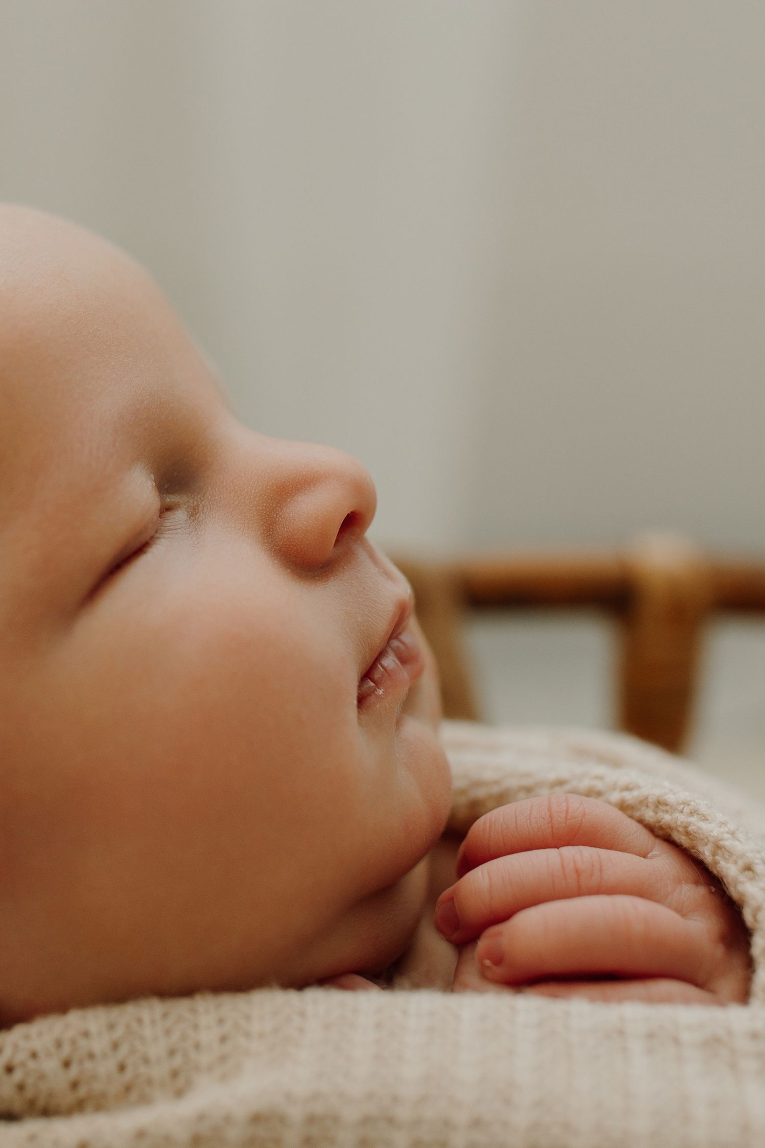 Close-up view of a sleeping baby's face with soft knitted blanket in warm natural lighting.