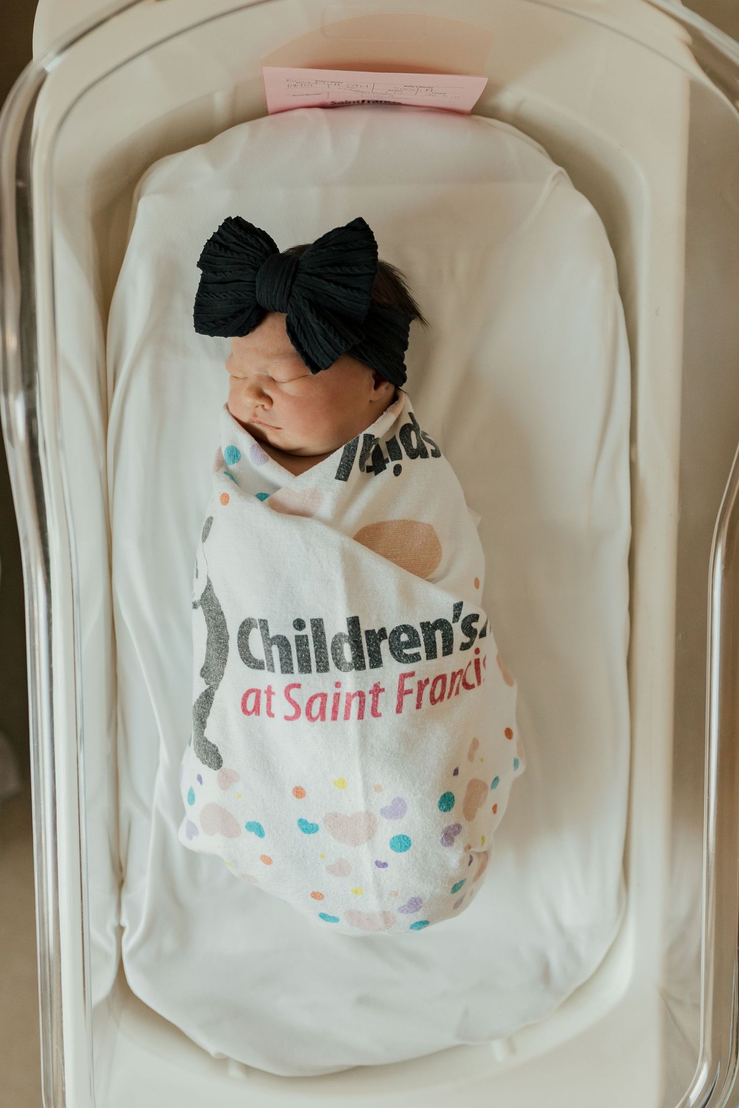 White hospital blanket with a Children's Hospital logo and colorful polka dot pattern folded neatly in a medical setting.