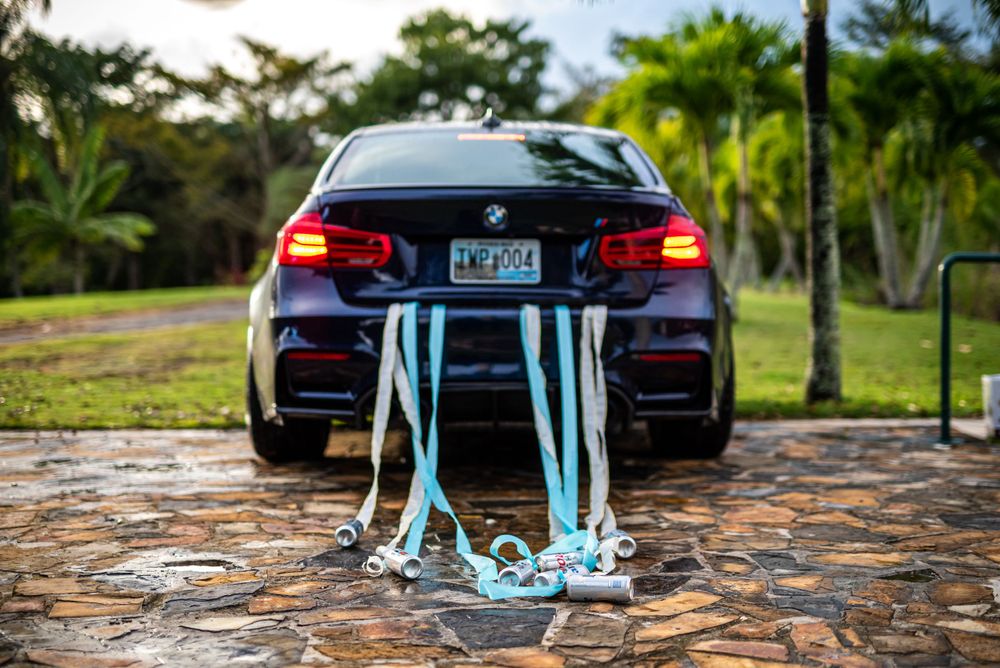 A black BMW decorated with light blue ribbons for a wedding celebration.