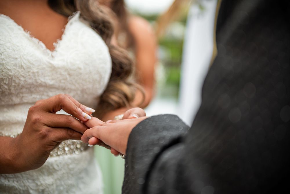 Close-up shot of hands during wedding ring exchange ceremony.