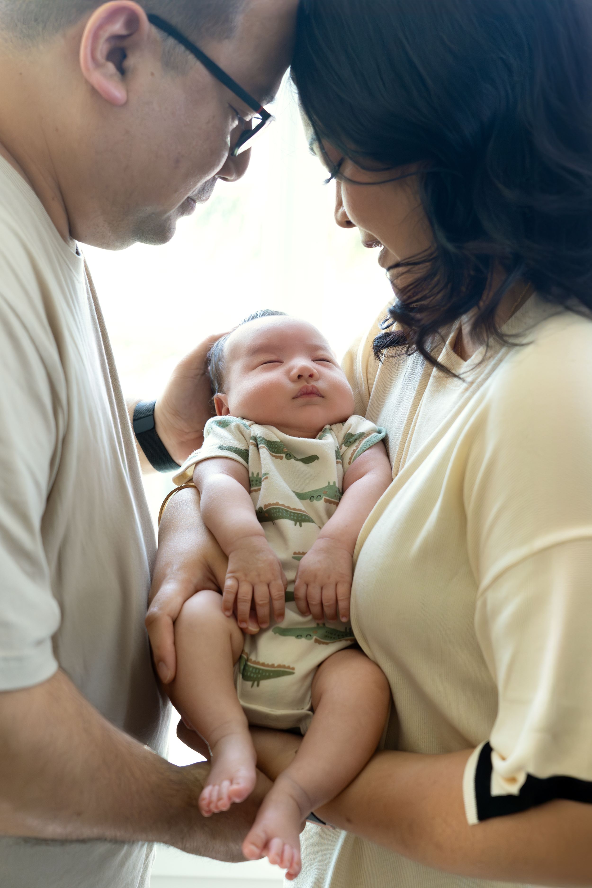 Parents sharing an intimate moment with their sleeping newborn baby.