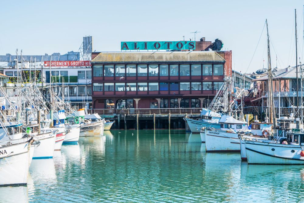 Modern waterfront restaurant building with boats docked in marina at Fisherman's Wharf.