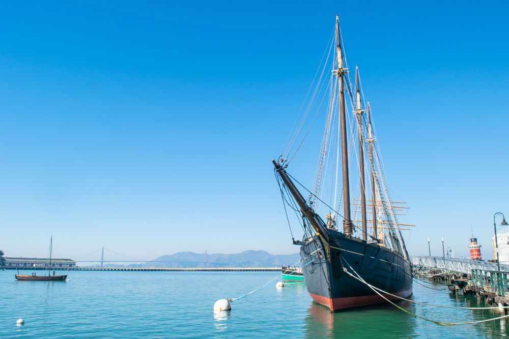A tall sailing ship docked in San Francisco Bay with clear blue skies overhead.