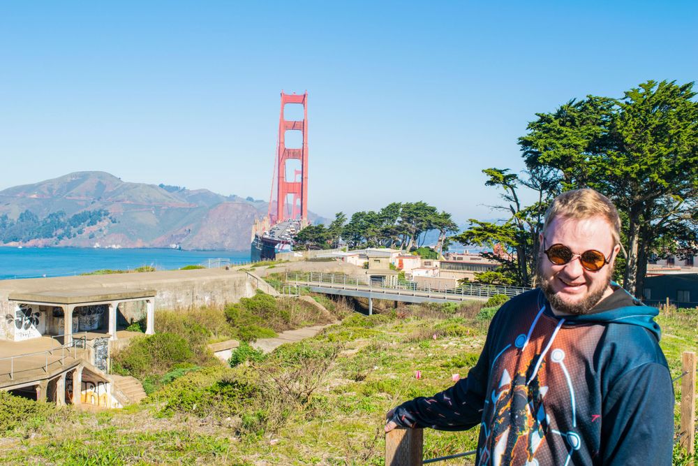 View of the Golden Gate Bridge from a scenic viewpoint with coastal vegetation.