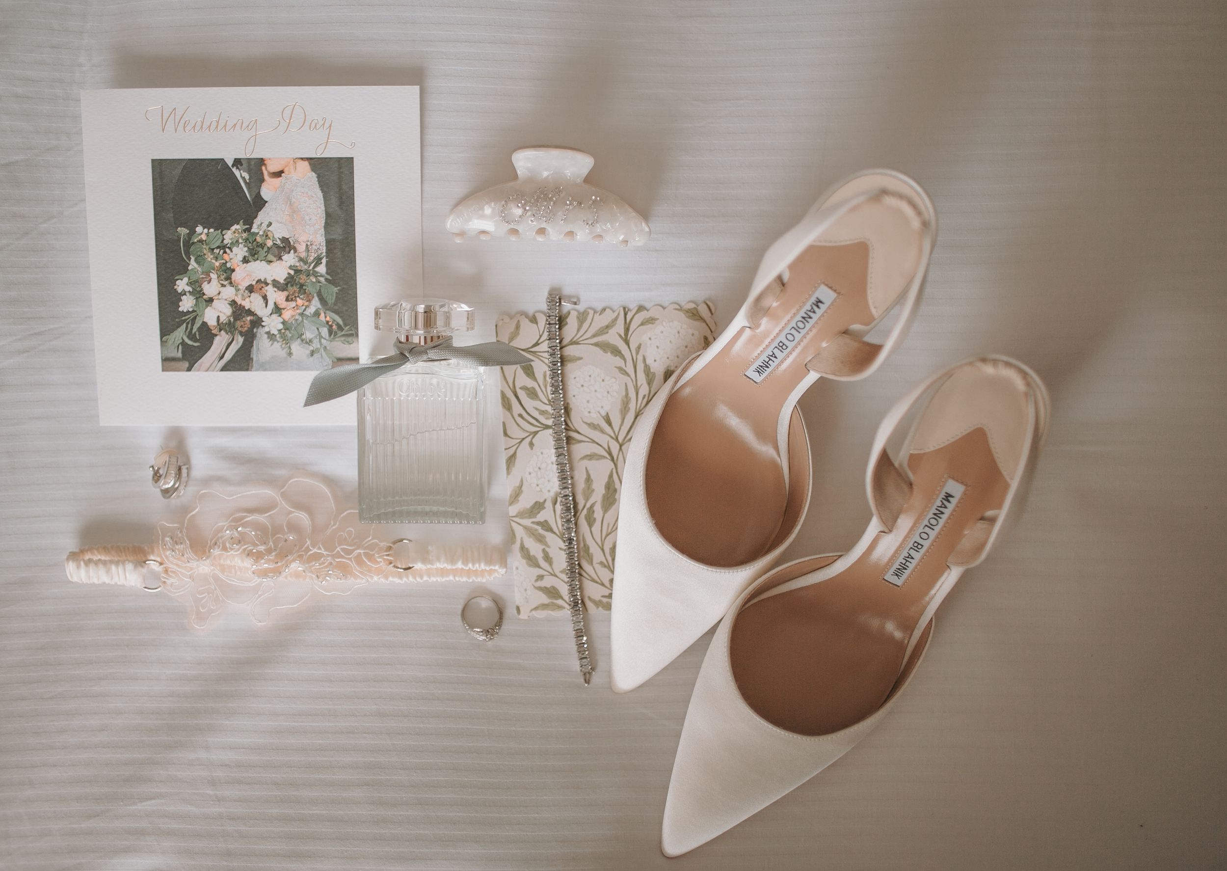 Wedding accessories including white heels and delicate decor arranged on light background.