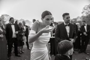 Black and white photo of a wedding celebration with guests enjoying champagne outdoors.