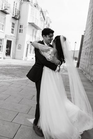 Black and white wedding photos of couple embracing on stone walkway.