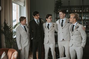 Groomsmen in light gray suits posing together at a wedding venue.