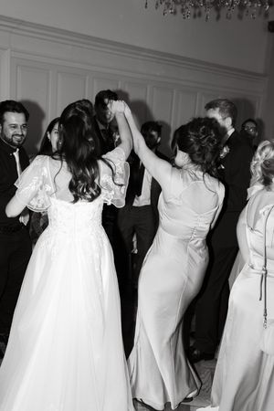 Wedding party dancing together in formal attire at reception venue.