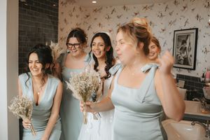 Wedding party wearing soft blue bridesmaid dresses share a joyful moment together.