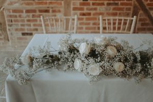 White floral arrangements and delicate baby's breath decorate a wedding reception table.