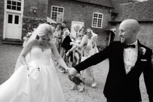 Wedding party celebrates outdoors with brick building backdrop.