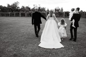 Wedding party walking across expansive lawn during outdoor celebration.