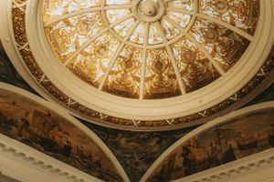 Ornate gold baroque ceiling with detailed architectural dome and decorative patterns.