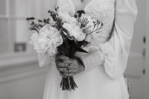 Elegant bridal details featuring white floral bouquets and wedding dress preparations.
