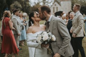 Wedding party celebration outdoors with guests in formal attire and floral arrangements.