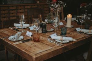 Rustic wooden tables set for an intimate wedding reception with wine glasses and place settings.