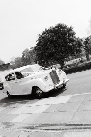 Classic white Rolls Royce wedding car parked on a street in black and white photography.