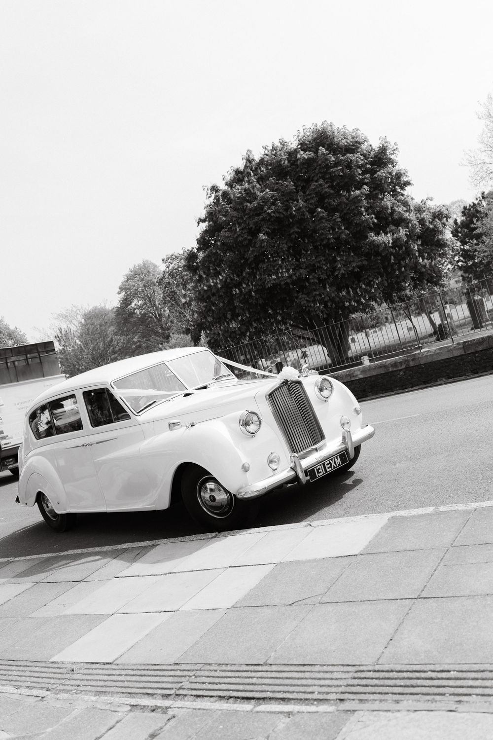 Classic white Rolls Royce wedding car parked on a street in black and white photography.