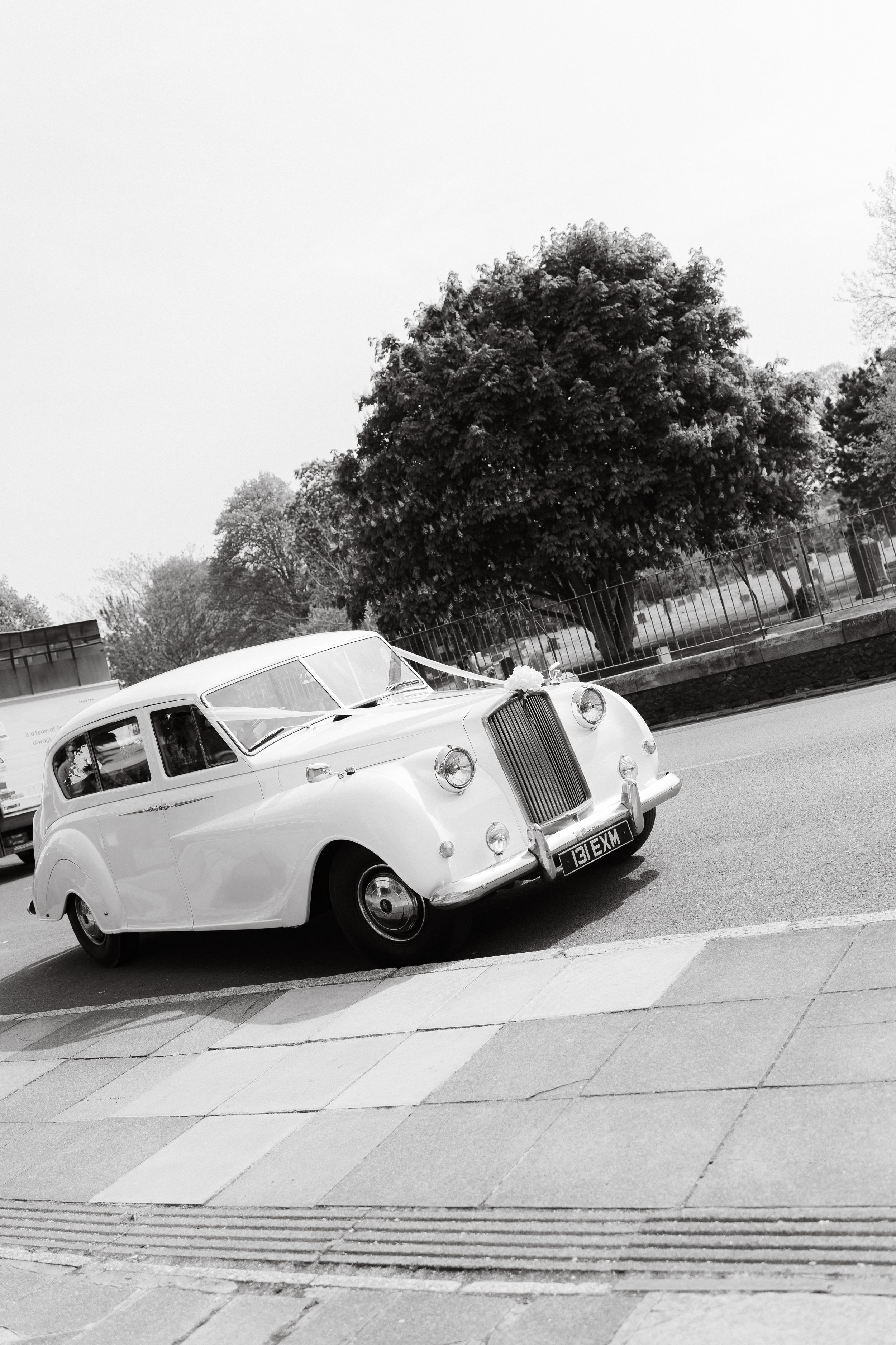Classic white Rolls Royce wedding car parked on a street in black and white photography.
