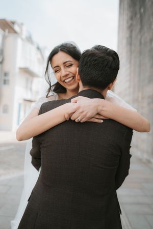 Intimate embrace captured during wedding photoshoot on urban street.