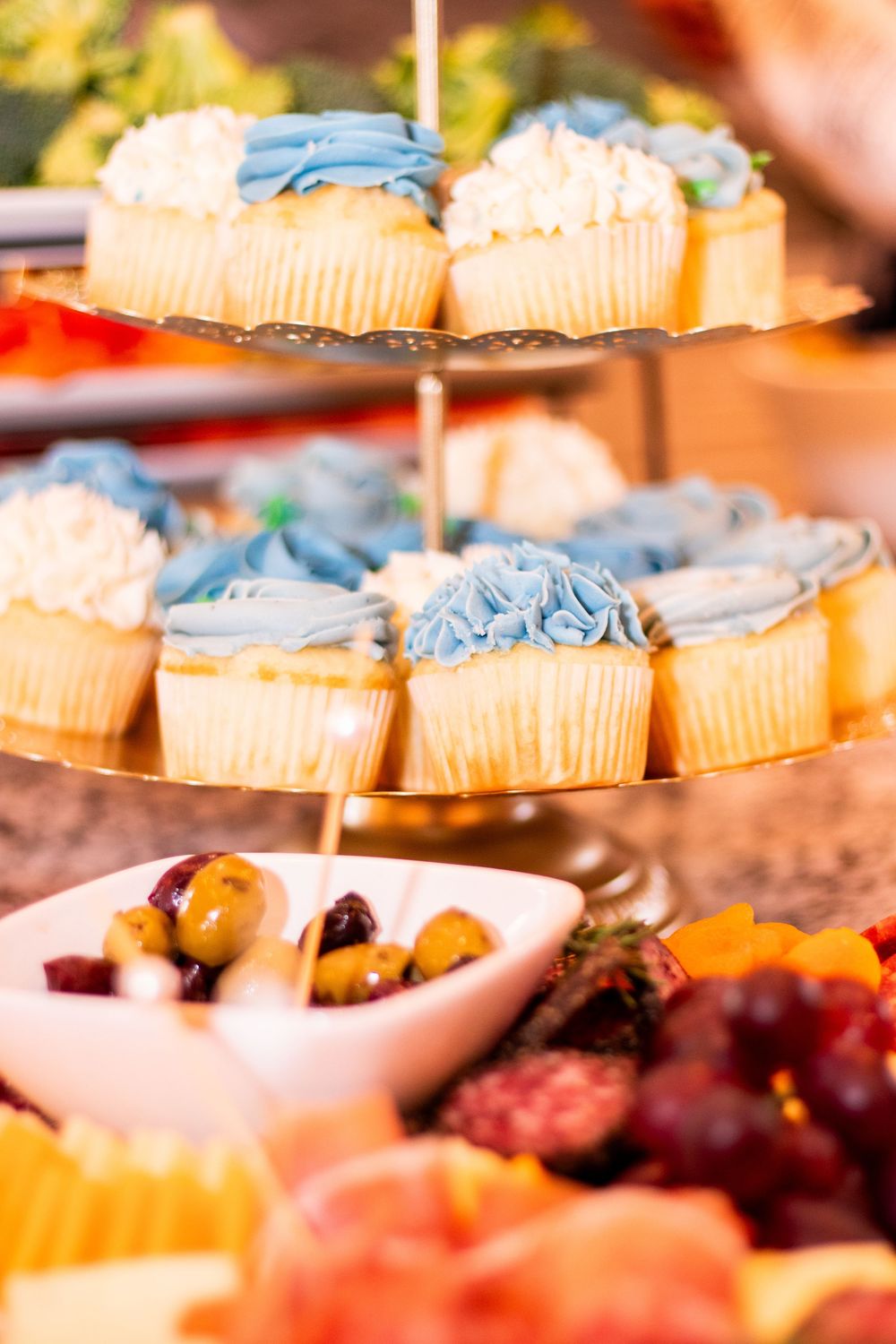 An assortment of colorful desserts and cupcakes with blue and white frosting displayed on serving platters at a party.