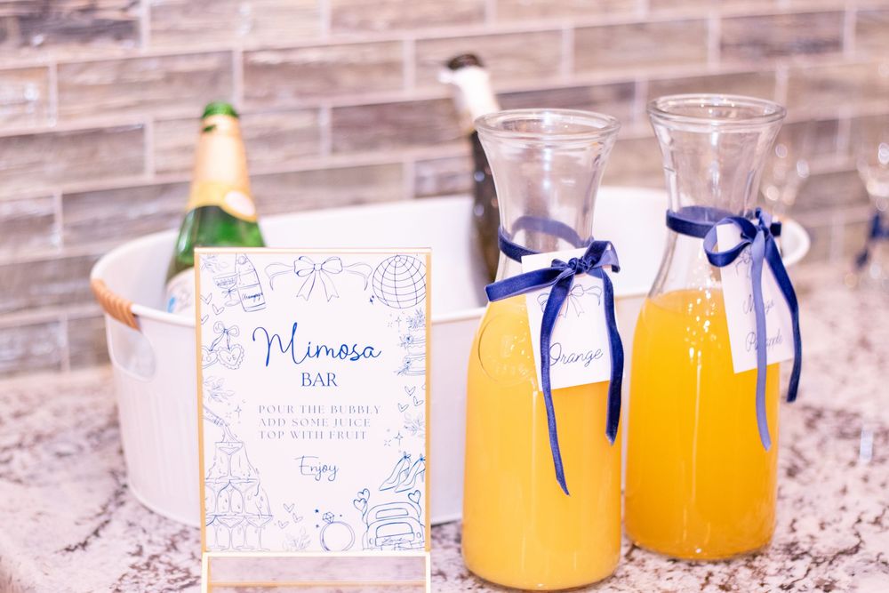 Glass bottles filled with fresh orange juice lined up on a rustic wooden surface with decorative tags and blue ribbons.