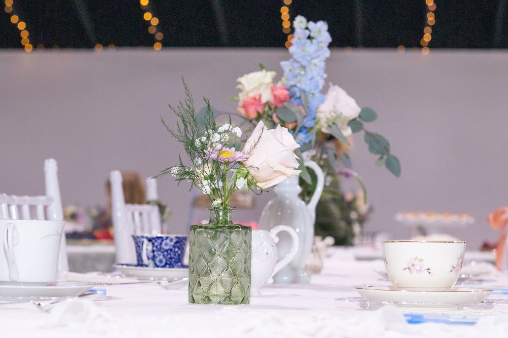 Elegant table settings with white floral centerpieces, blue and white china, and crystal glassware at a baby shower.