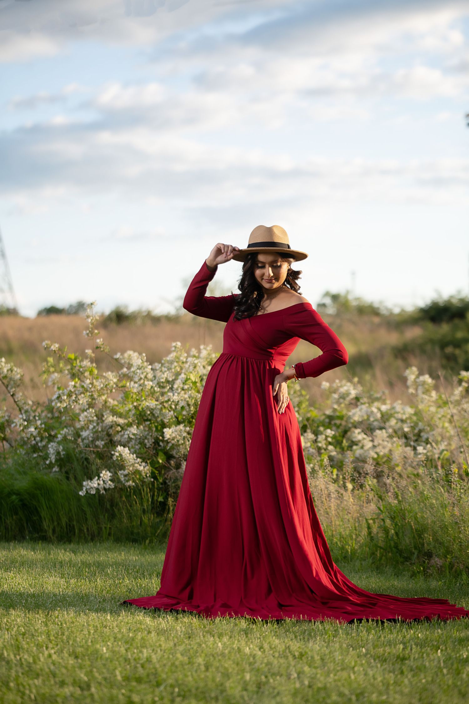 A flowing red dress contrasts with wildflowers in a sunny meadow.