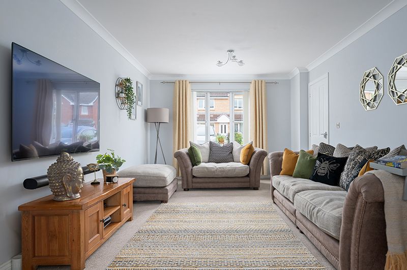 Modern living room interior with gray sofa, wooden furniture, and natural light streaming through large windows.
