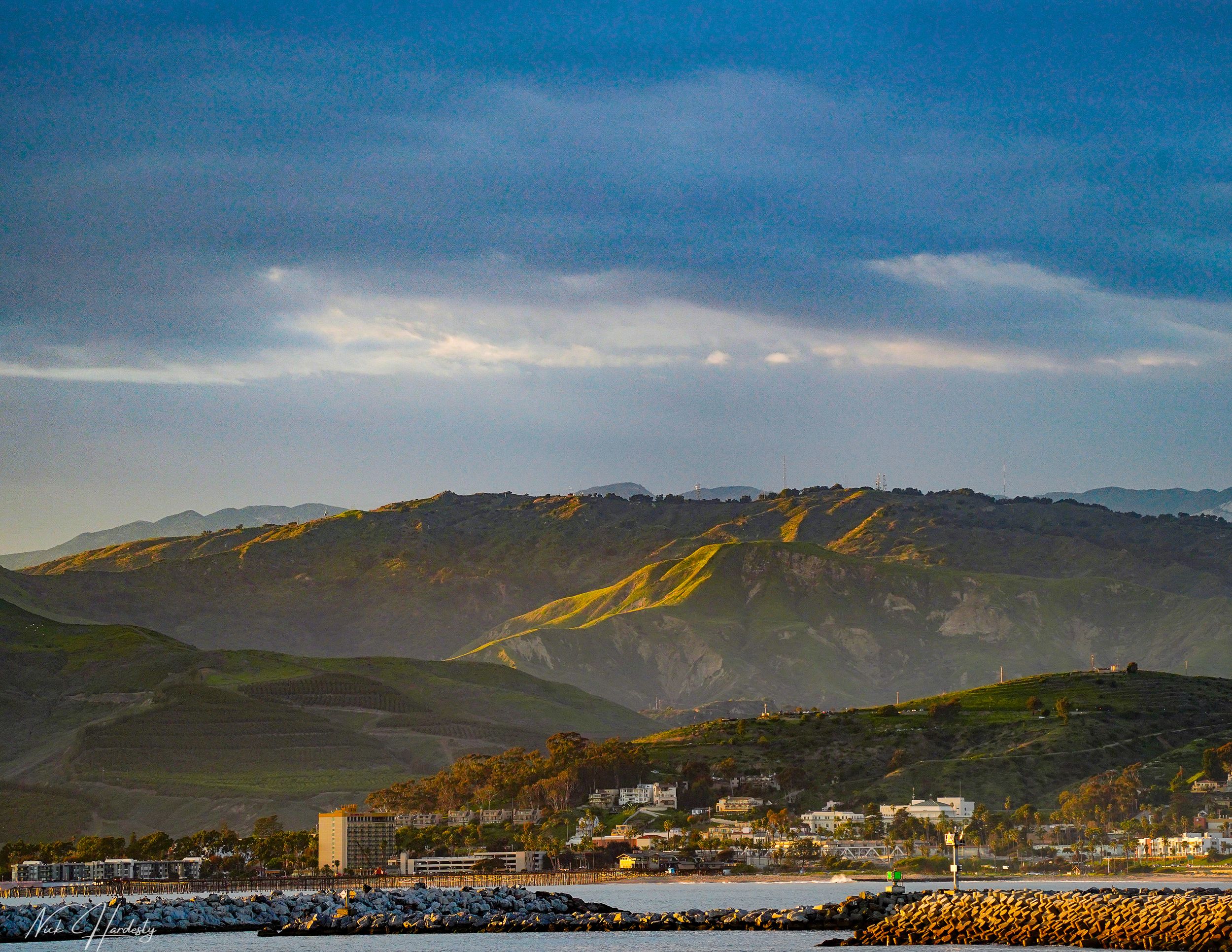 Sunset over Ventura Harbor with rich purple and orange hues reflecting on the calm water.
