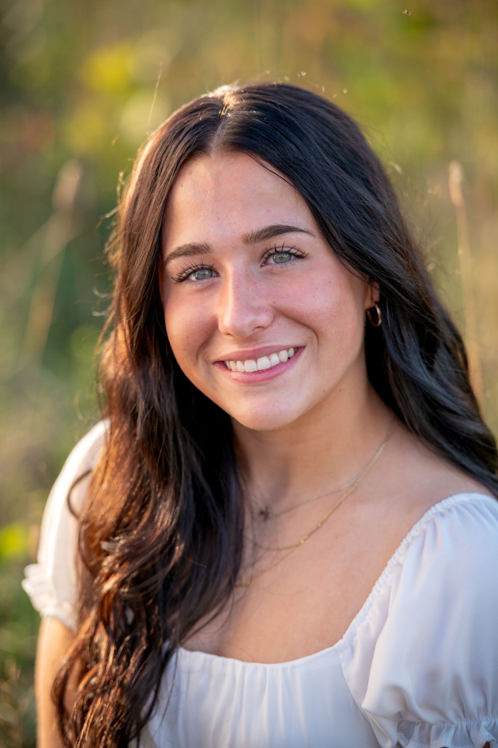 A white peasant dress complements natural lighting in an outdoor portrait.