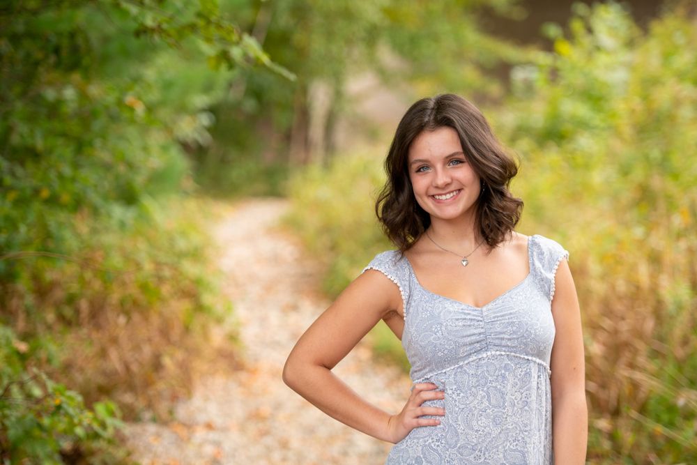 A grey sundress complements natural lighting on a wooded nature trail.