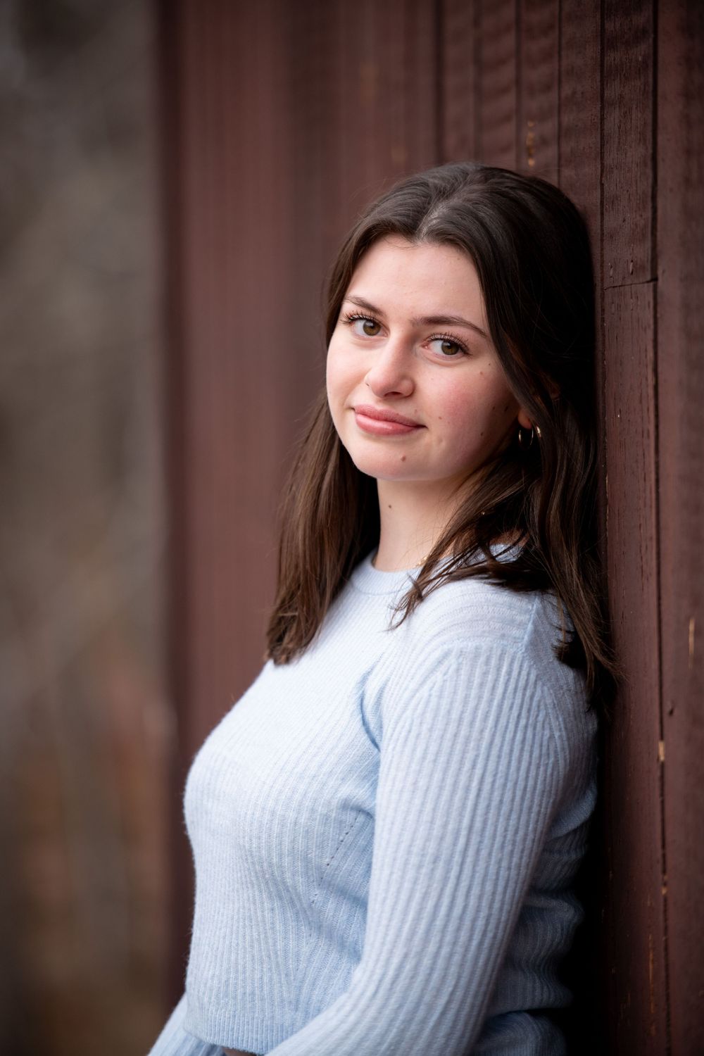 Portrait collection showing poses in a soft blue sweater against wooden panels.