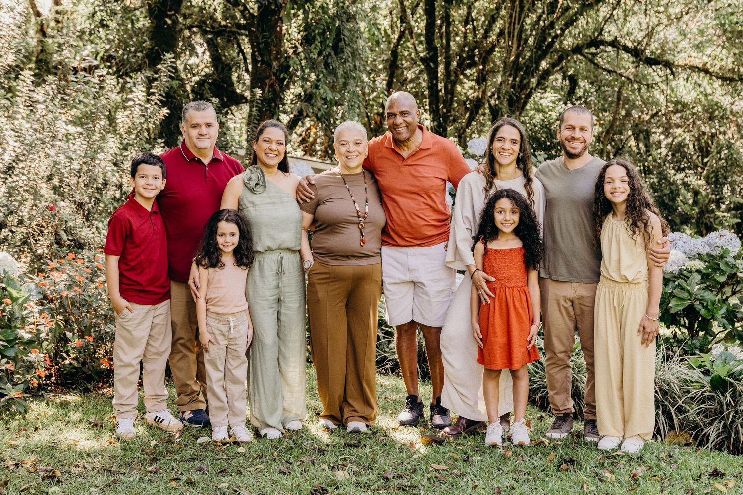 Extended family group poses together in coordinated white and neutral outfits against tropical background.