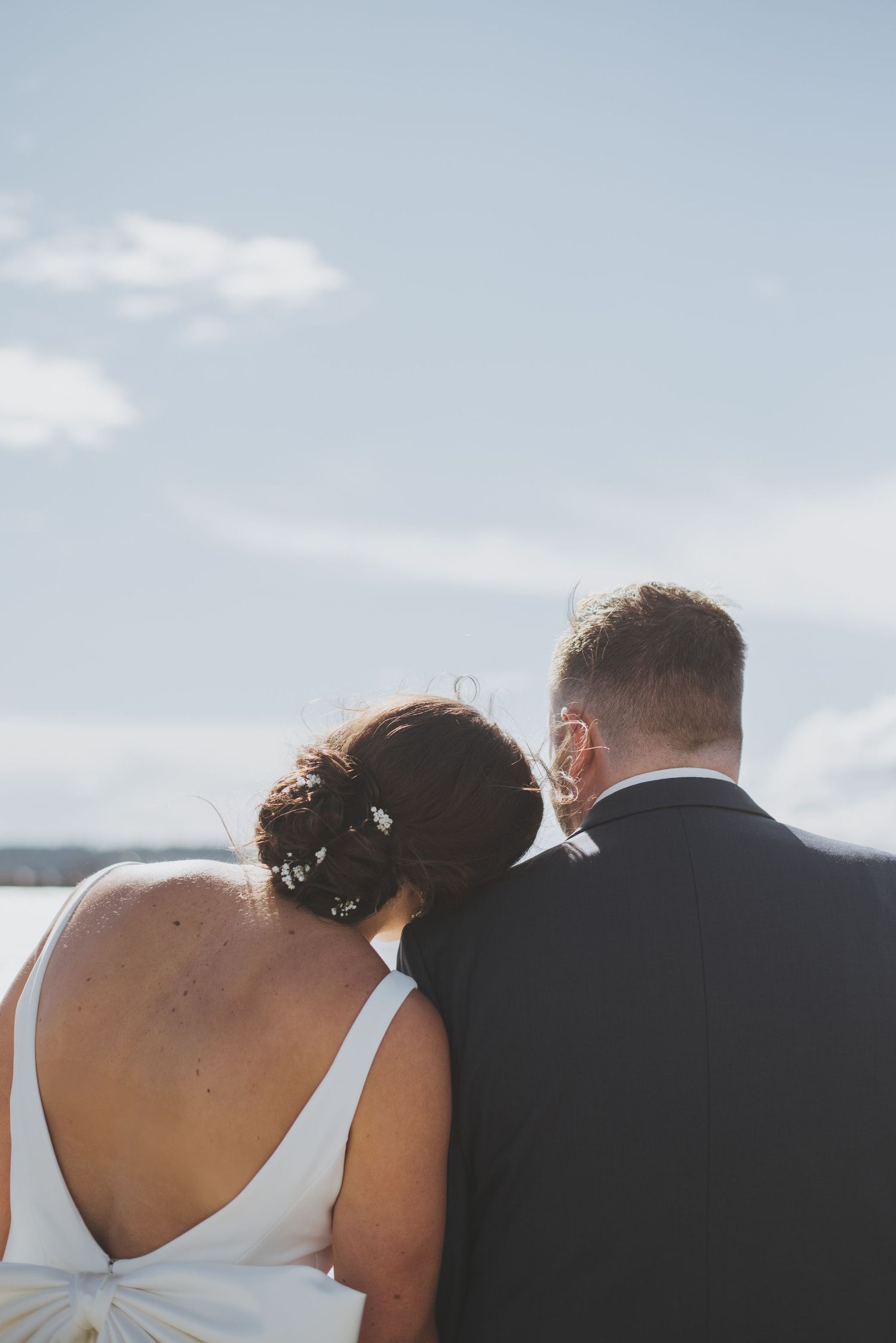 A romantic moment between newlyweds overlooking the water on their wedding day.