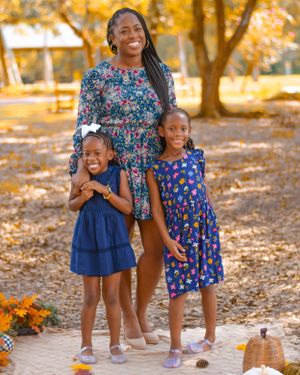 Children playing and laughing together on an autumn path with orange flowers and fallen leaves.