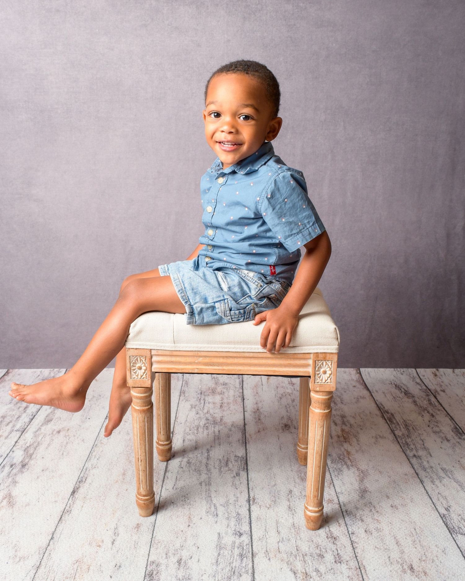 Studio portrait series of small child in denim outfit playing on wooden bench against grey background.