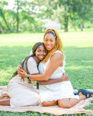 Friends share joyful moments while relaxing on a blanket in a sunny green park.