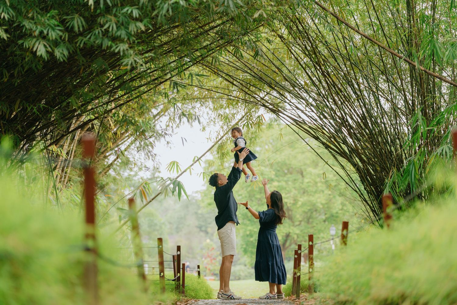A person in a dress walks through a lush bamboo forest pathway creating a dreamy natural scene.