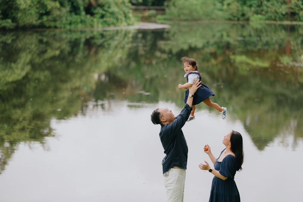 A couple shares a romantic dance together by a serene lake surrounded by lush greenery.