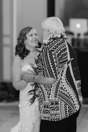 Bride dancing with her father on her wedding day. She is beaming and looking up at him.
