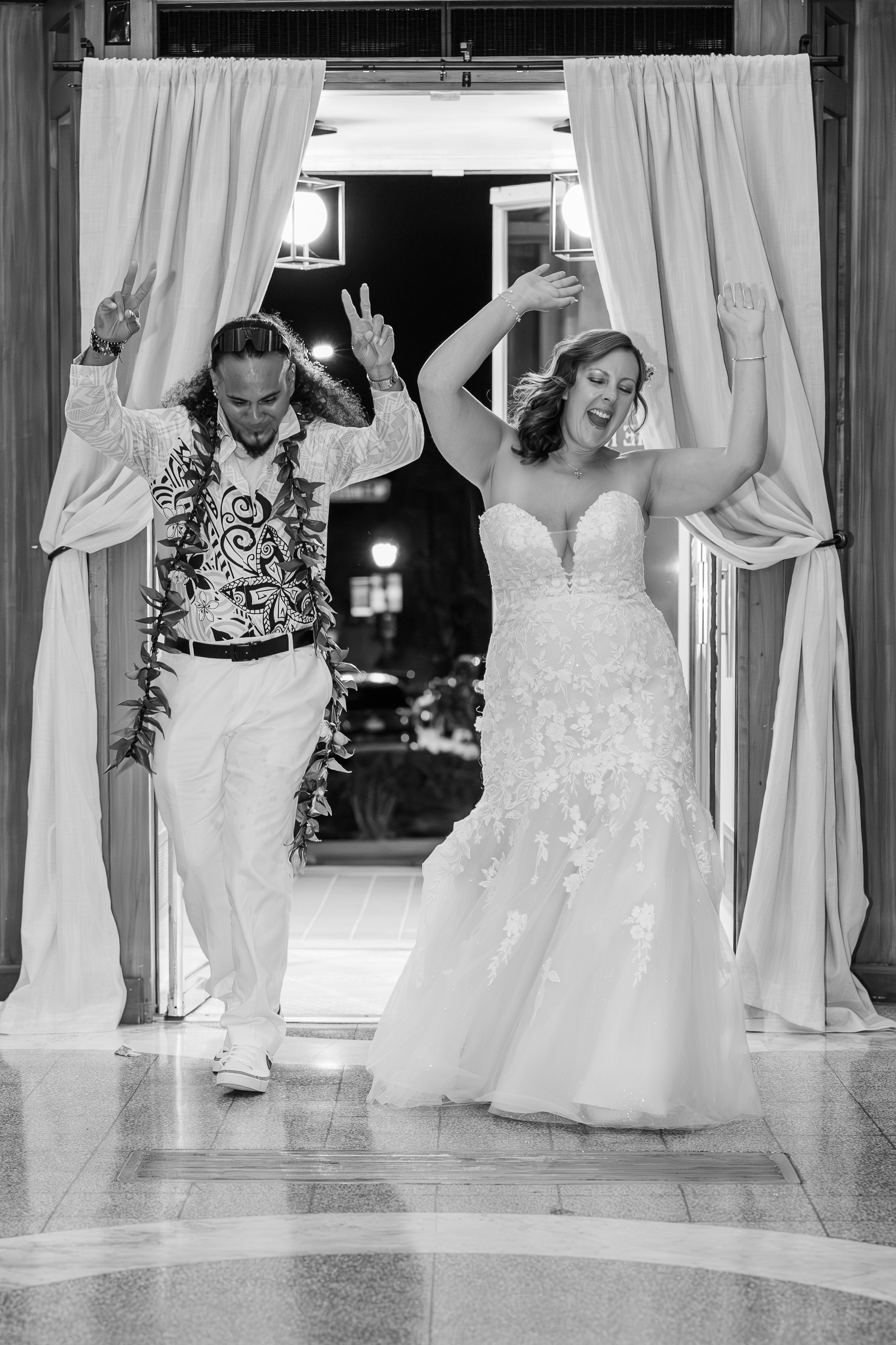 Bride and groom dancing as they enter the reception room during their grand march in black and white.