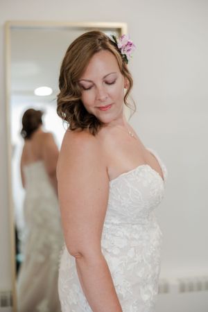 Brides wearing her white wedding dress looking down softly over her shoulder at her train.