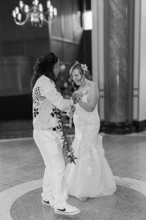 Bride  with a big smile dancing with her groom at their first dance in black and white.