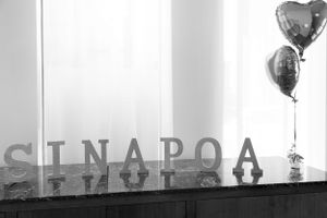 Letters on a counter spelling out the grooms last name at his wedding with two heart balloons in black and white.