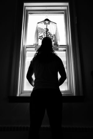 Groom looking up at the shirt he is about to wear for his ceremony. The lighting is very strong in black and white.